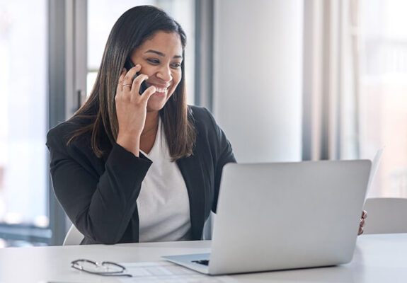 Woman using phone while on laptop