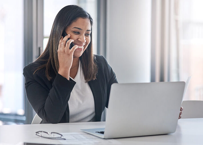 Woman using phone while on laptop